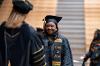 Acting President Dr. Shonna Riedlinger shakes hands with a graduate while handing her a degree.