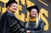 Acting President Dr. Shonna Riedlinger shakes hands with a graduate while handing her a degree.